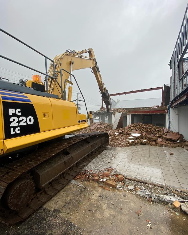 A Large Yellow Excavator Is Demolishing A Building — Ballina Demolitions In Tweed Heads, NSW