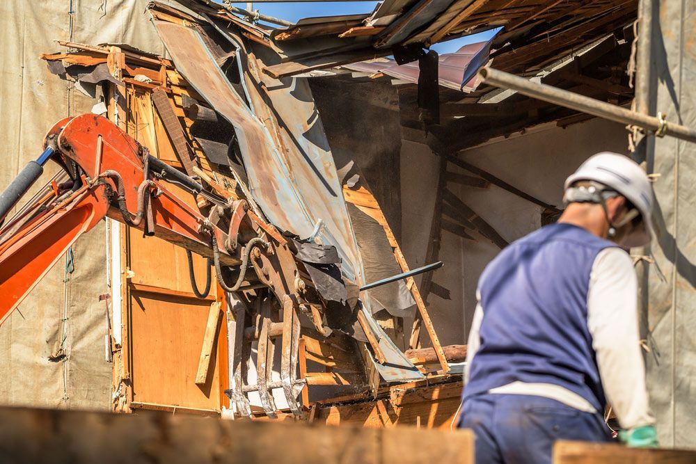 A Man Is Standing In Front Of A Building That Is Being Demolished — Ballina Demolitions In Kyogle, NSW