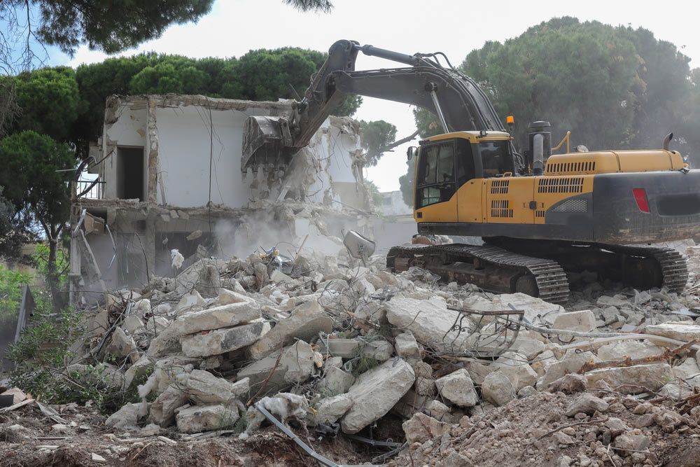 A Large Yellow Excavator Is Demolishing A Building — Ballina Demolitions In Tweed Heads, NSW