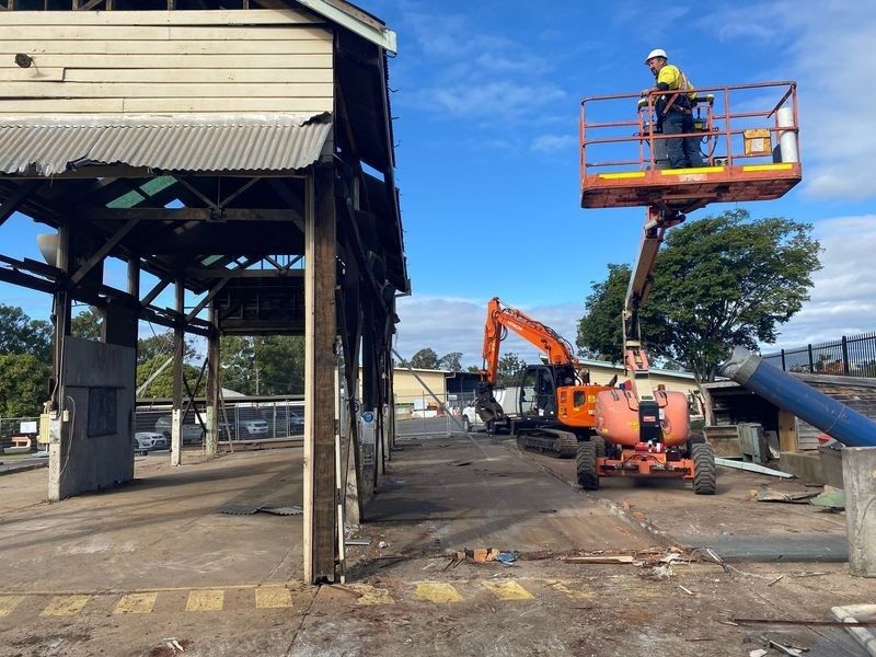 A Man Is Standing On A Lift In Front Of A Building — Ballina Demolitions In Byron Bay, NSW