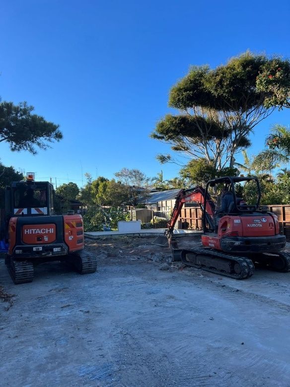 Two Excavators Are Parked Next To Each Other In A Gravel Lot — Ballina Demolitions In Byron Bay, NSW