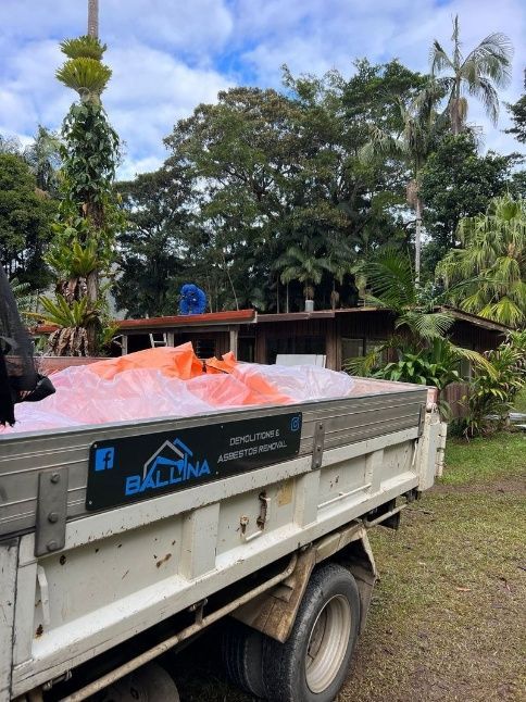 A White Dump Truck Is Sitting In A Dirt Field With Trees In The Background — Ballina Demolitions In Byron Bay, NSW