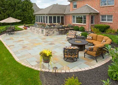 A large patio with furniture and a fire pit in front of a brick house.