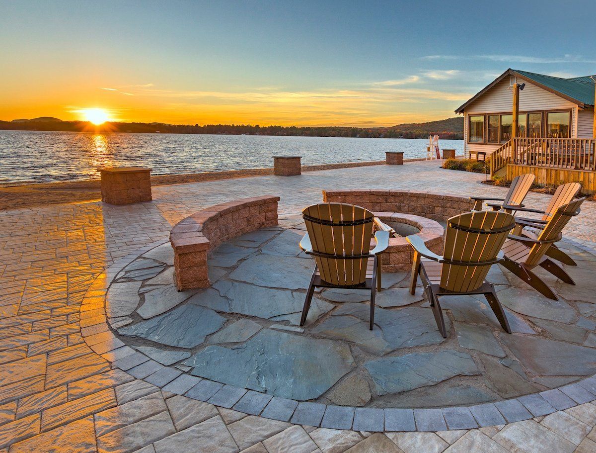 There is a fire pit in the middle of the patio with chairs around it.