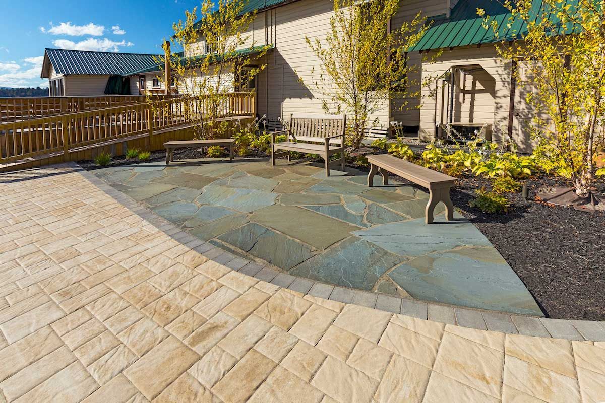 A patio with a table and chairs on it in front of a house.