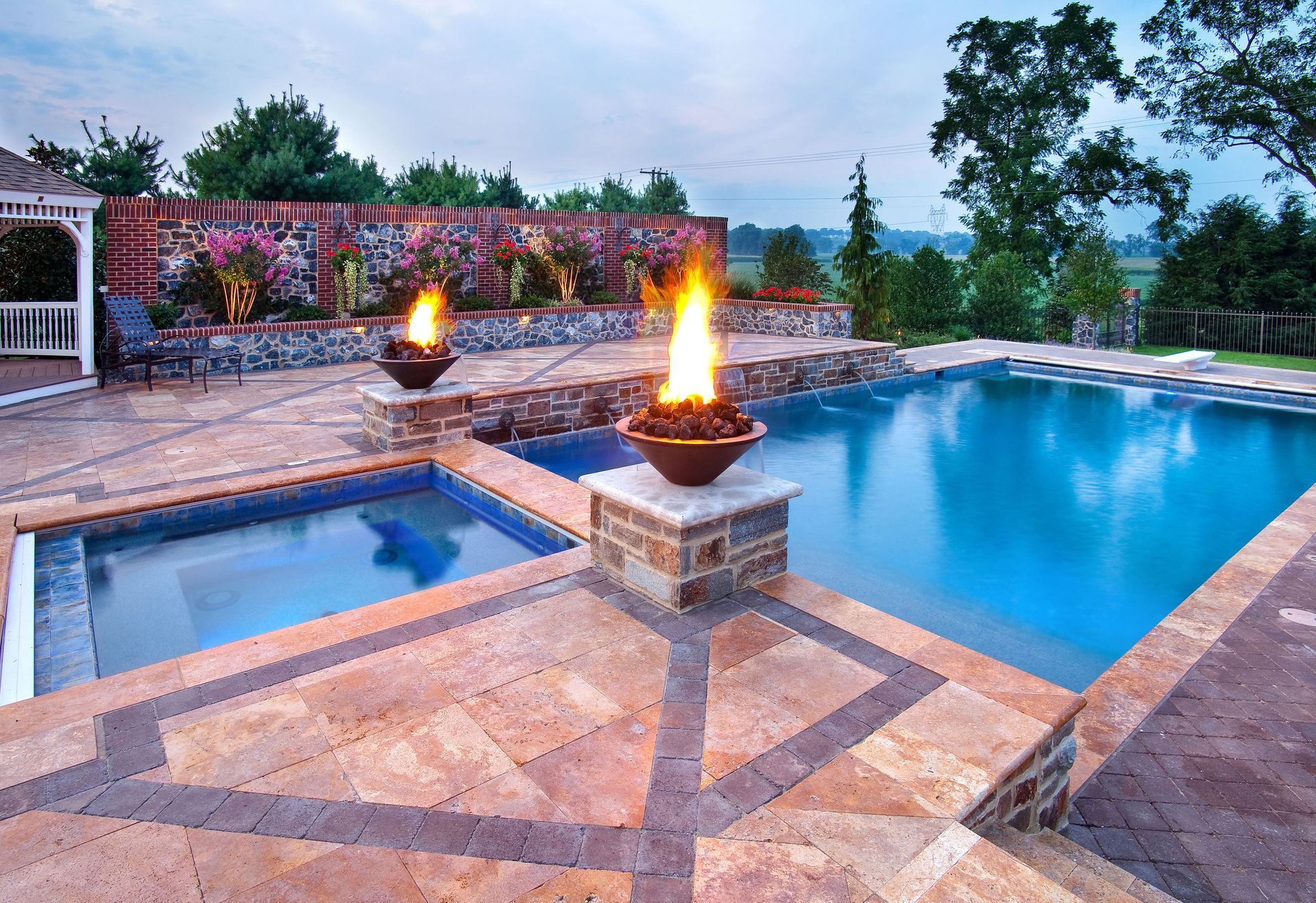 A swimming pool with a fire pit and a gazebo in the background