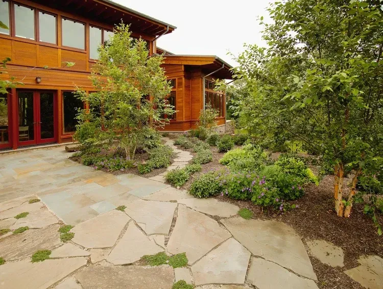 A large wooden house with a stone walkway in front of it