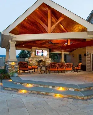 A covered patio with a fireplace and a television