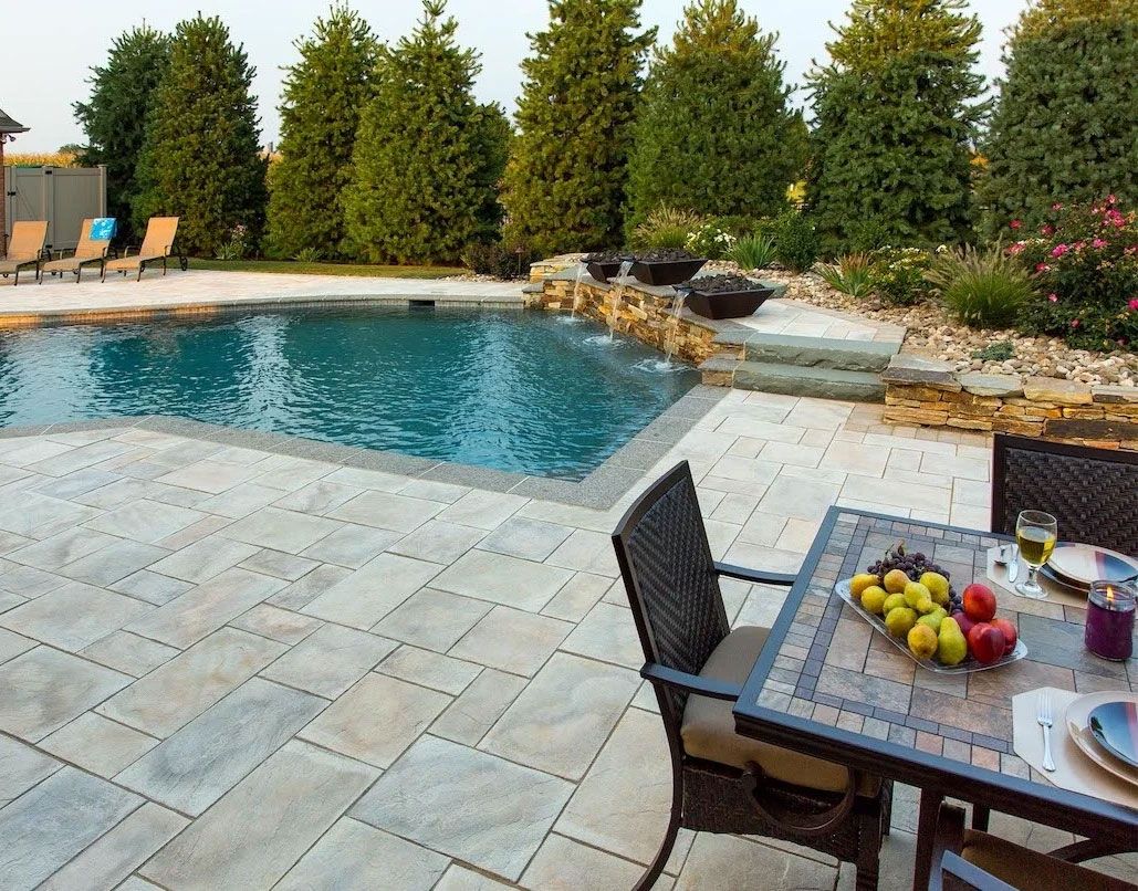 A patio with a table and chairs and a large swimming pool