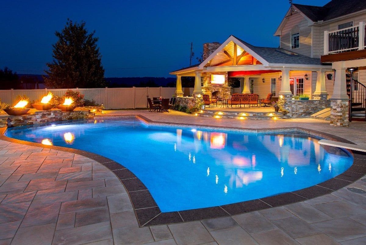 A large swimming pool in front of a house at night