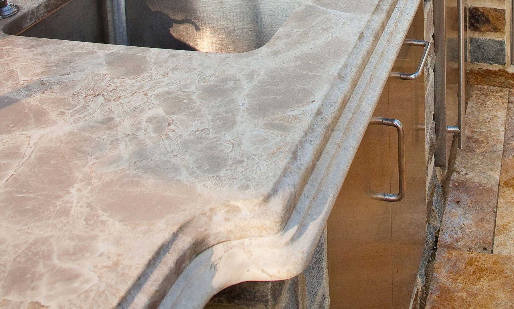 A kitchen sink with a granite counter top and stainless steel handles.
