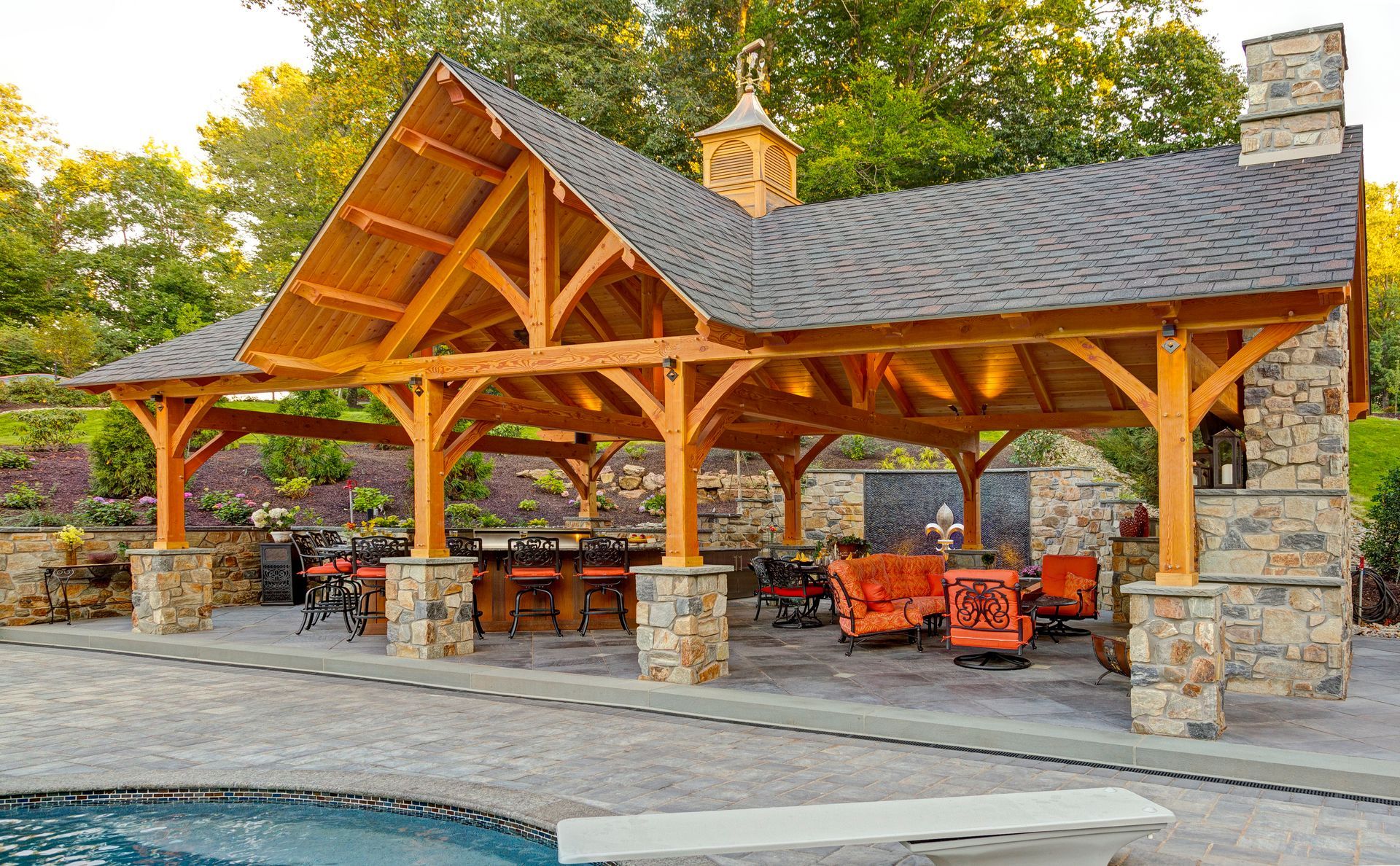 A large wooden pavilion is sitting next to a swimming pool.