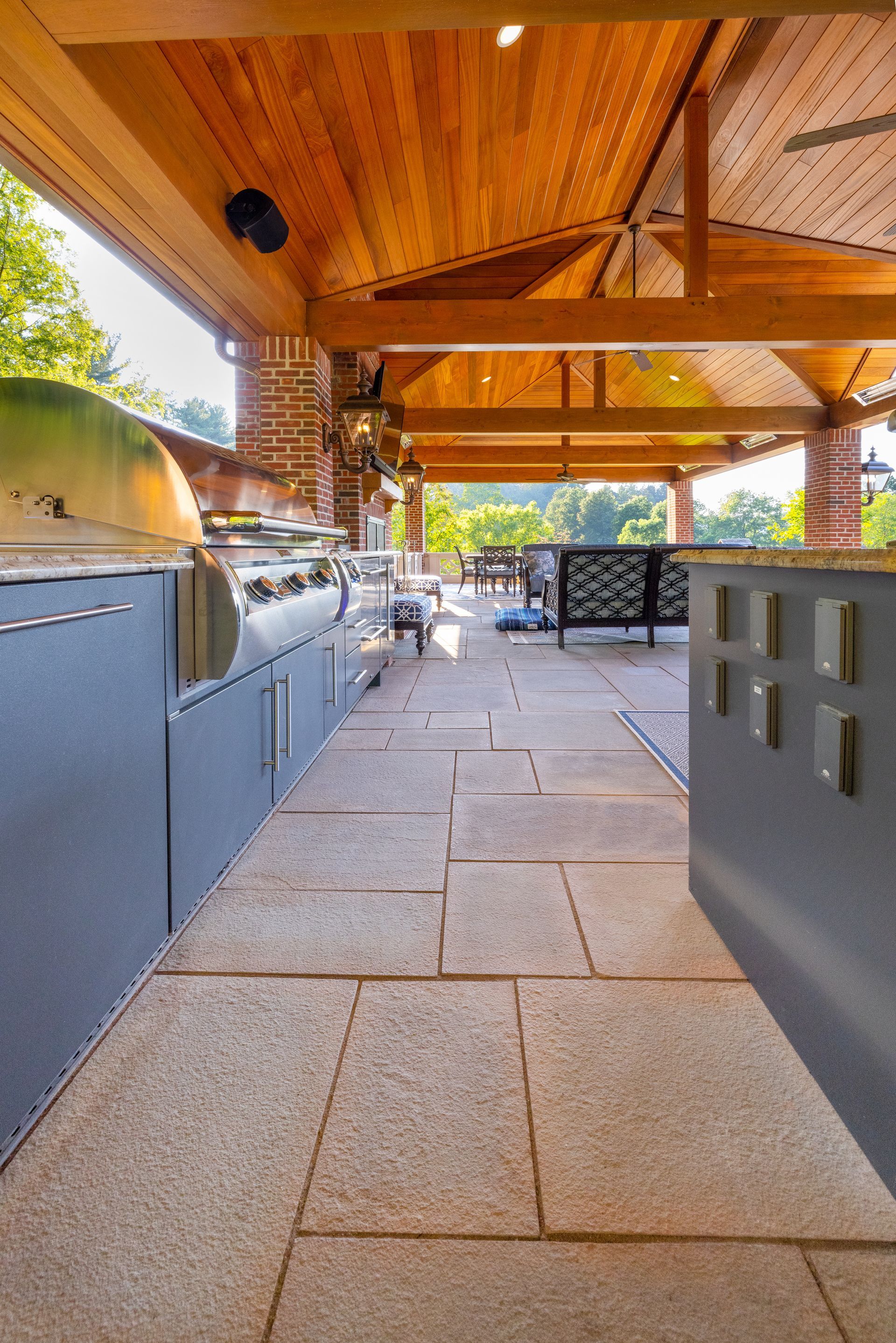 A large outdoor kitchen with a wooden ceiling and a grill.