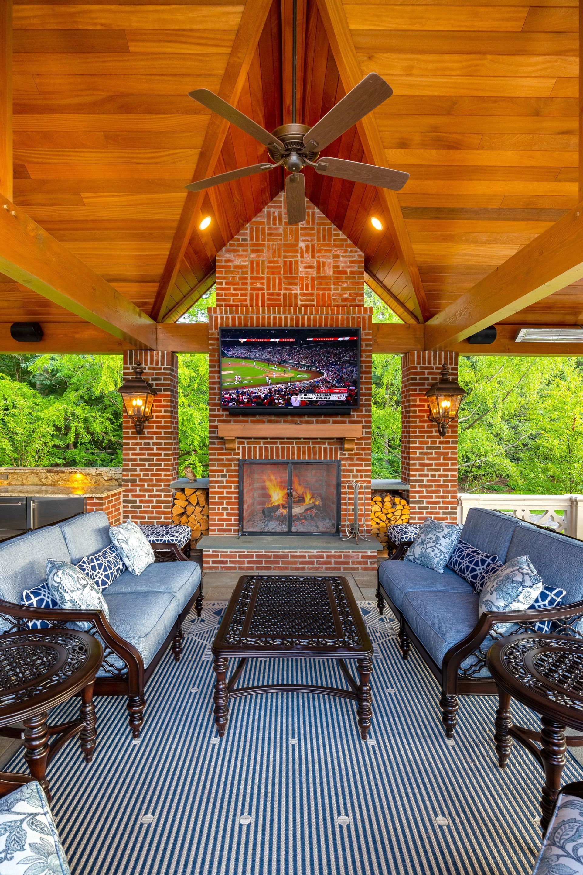 A living room with a fireplace , couch , chairs , table and television.
