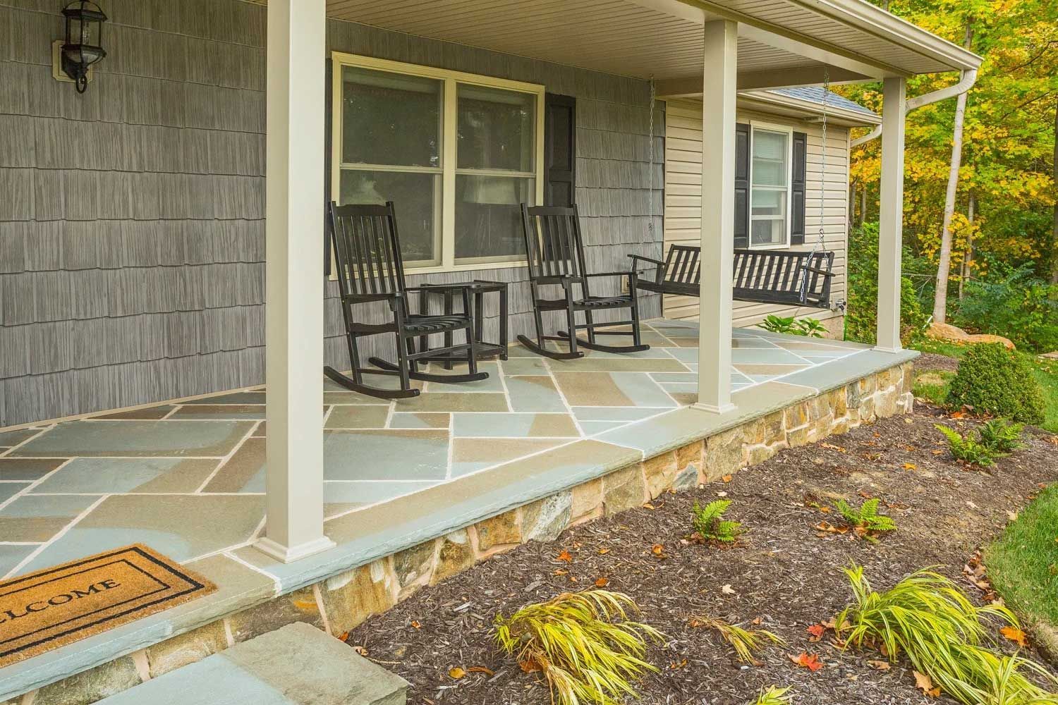 There are rocking chairs on the porch of a house.