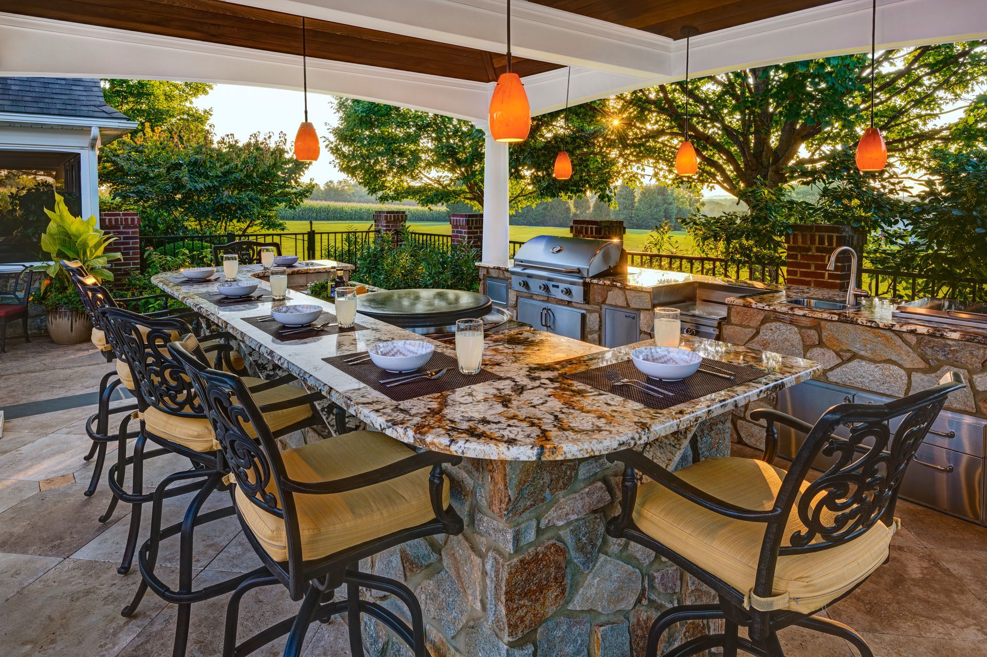 A patio with a long table and chairs and a grill.