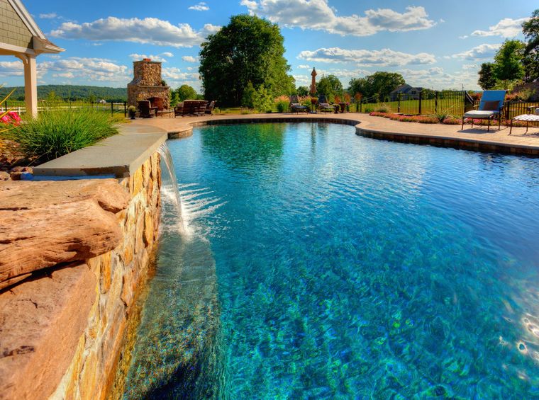 A large swimming pool with a waterfall in the middle A large swimming pool with a waterfall in the middle
