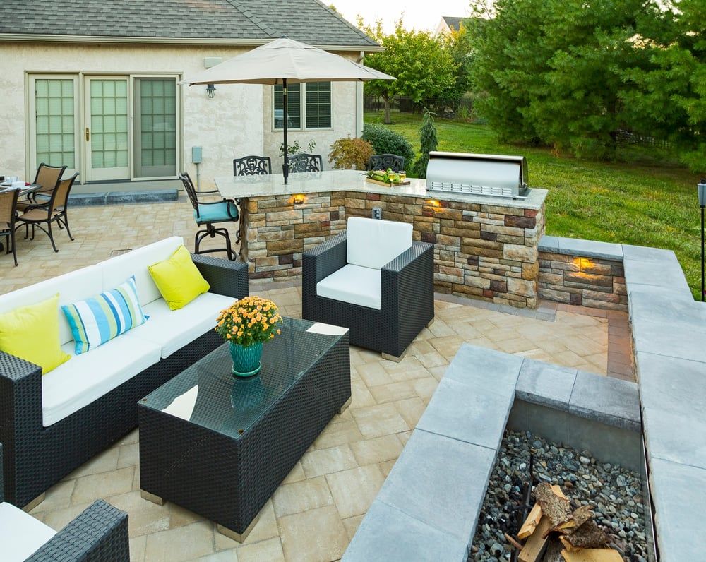 A patio with a table and chairs on it in front of a house.