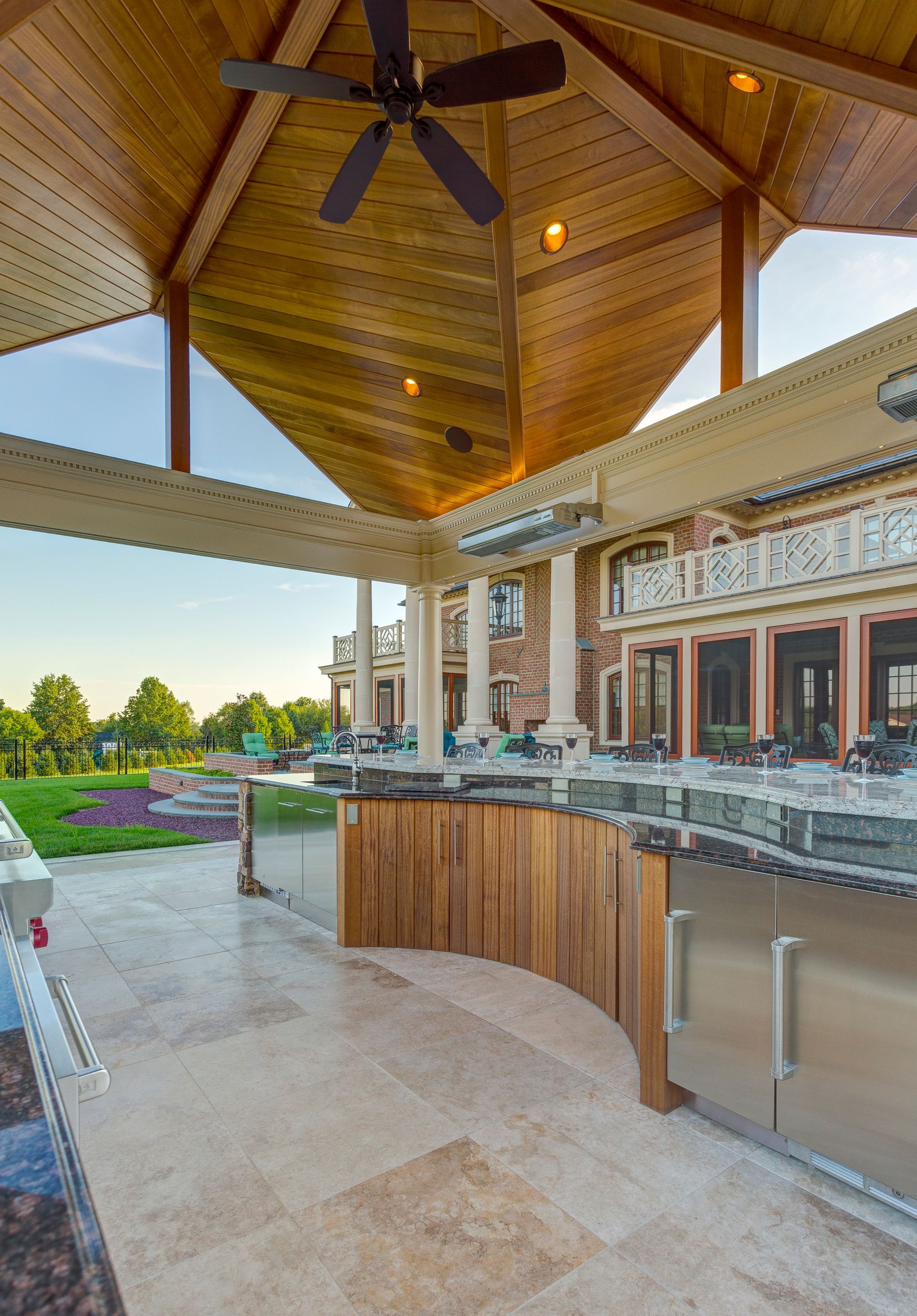 A large outdoor kitchen with a ceiling fan and stainless steel appliances.