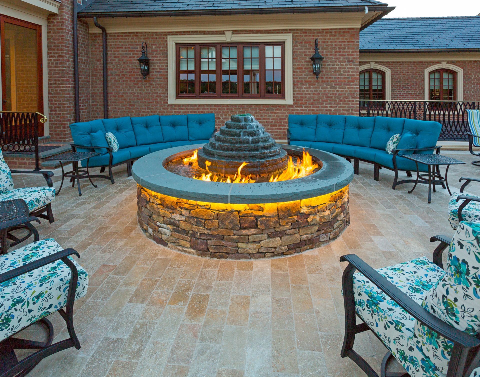 There is a fire pit in the middle of the patio surrounded by furniture.