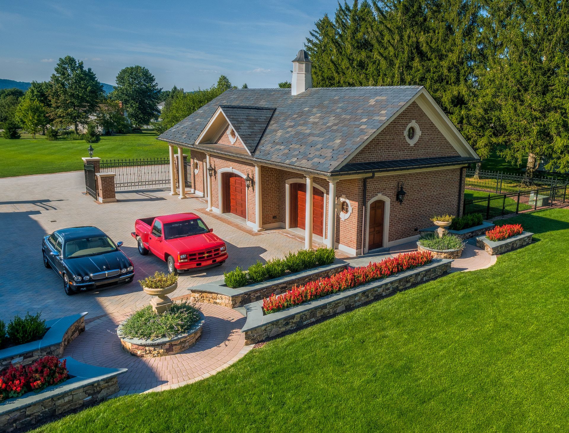 Two cars are parked in front of a large brick house.