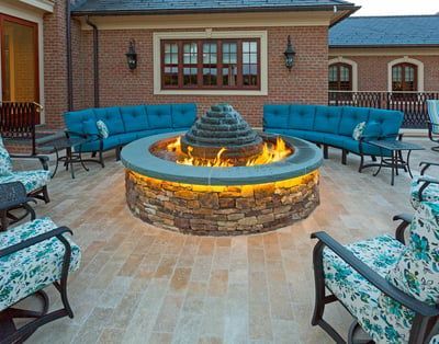 There is a fire pit in the middle of the patio surrounded by furniture.