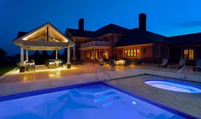 A large house with a swimming pool in front of it at night.