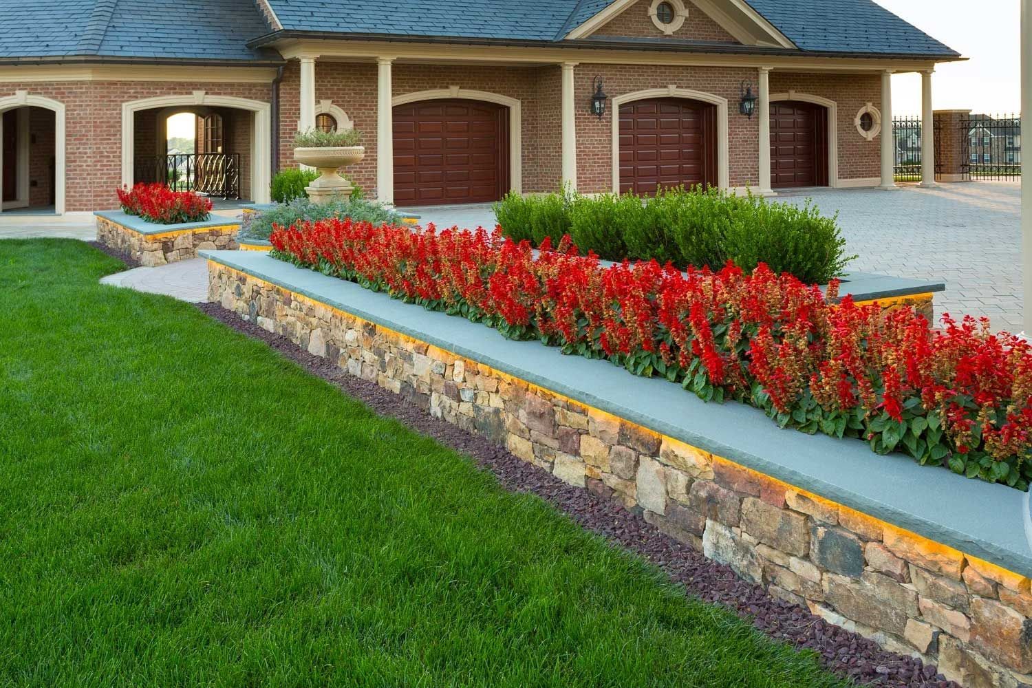 A house with a stone wall and flowers in front of it