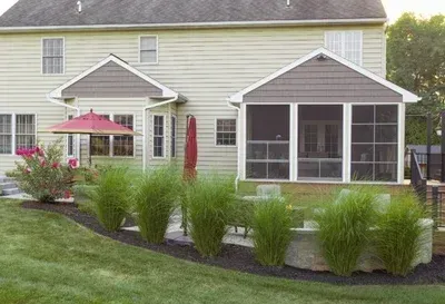 A screened in porch with a red umbrella in front of a house.