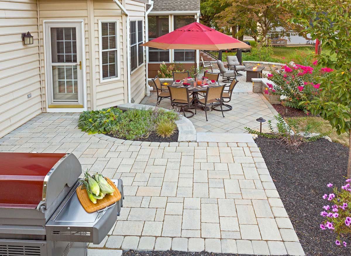 A patio with a grill and a red umbrella