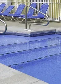 A swimming pool surrounded by blue chairs and a fence