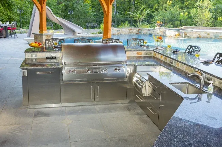 A stainless steel outdoor kitchen with a slide in the background.