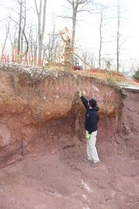 A man is standing next to a large pile of dirt.