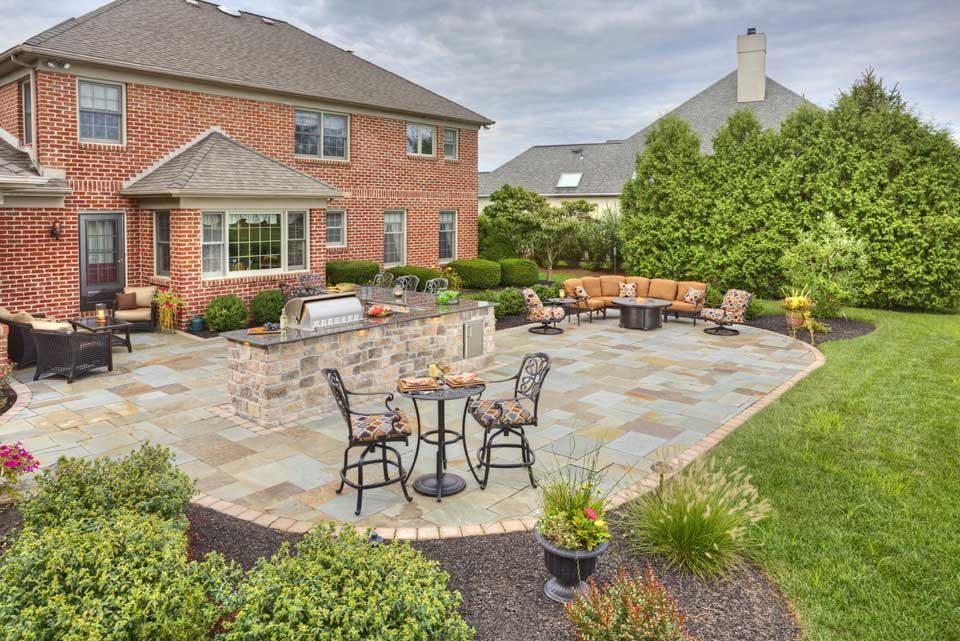A patio with a table and chairs on it in front of a house.