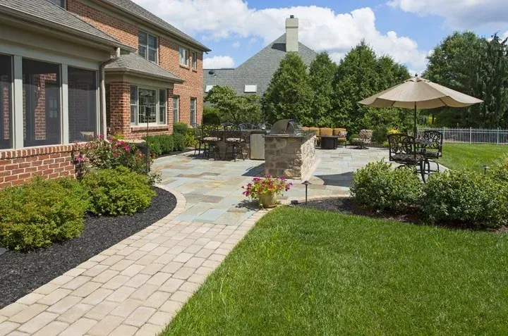 A large brick house with a patio and umbrellas in front of it.