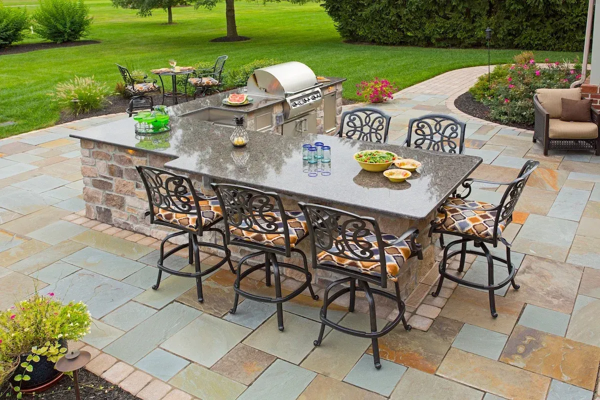 A patio with a table and chairs and a grill.