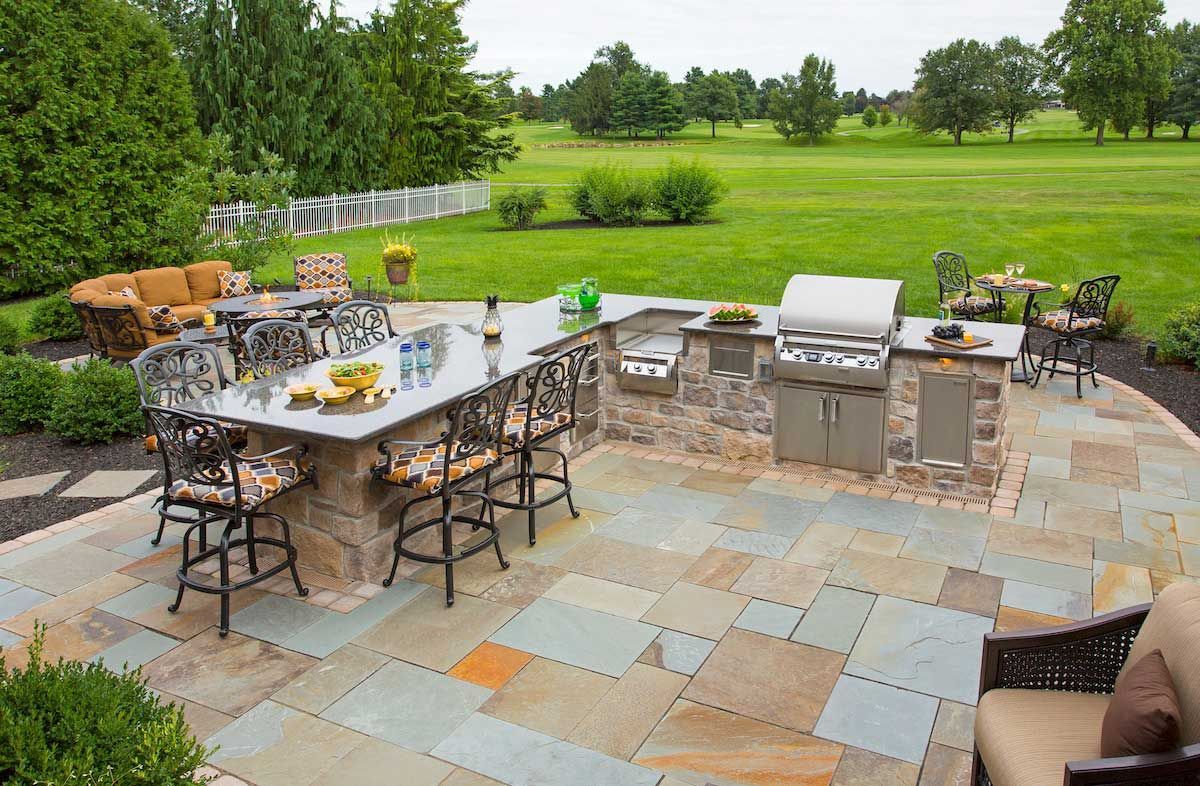 A patio with a table and chairs on it in front of a house.