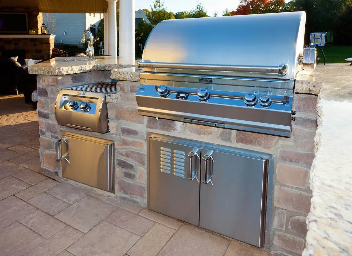 A stainless steel grill is built into a brick wall.