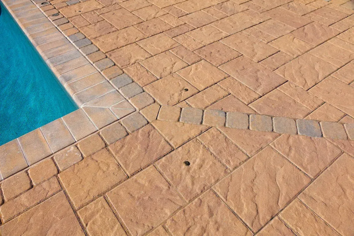 A close up of a brick patio next to a pool