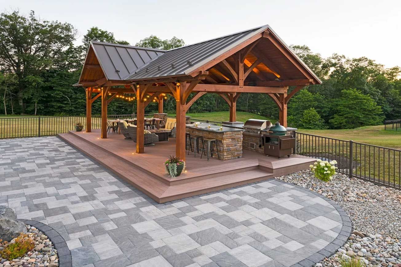 A large wooden pavilion with a brick patio in front of it.