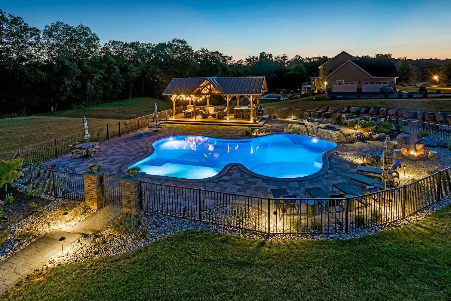 An aerial view of a large swimming pool with a gazebo in the background at night.