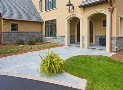 A large house with a driveway and a lawn in front of it.
