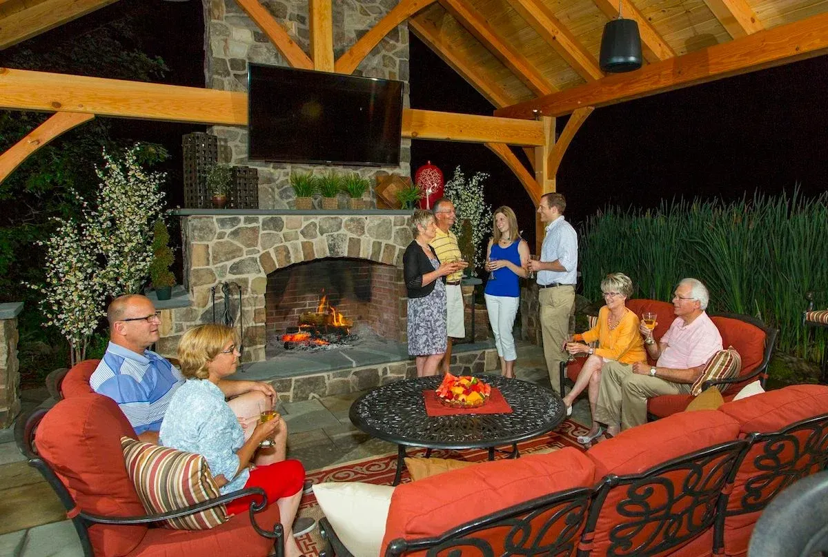 A group of people are sitting in front of a fireplace.