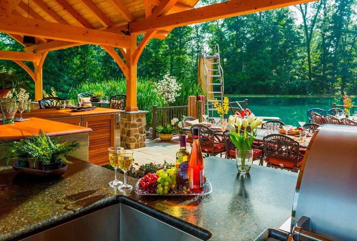 A kitchen with a sink , a grill , a bottle of wine , grapes , and glasses of wine.
