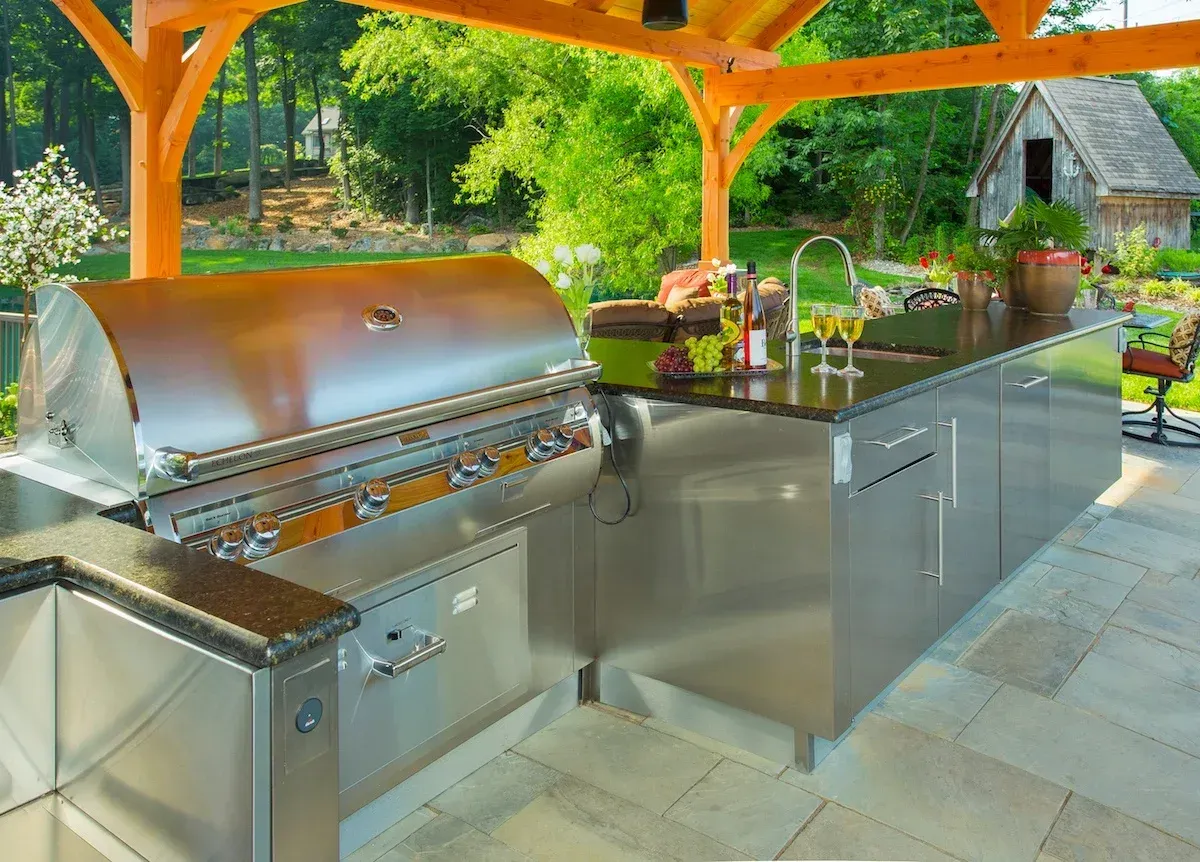 An outdoor kitchen with stainless steel cabinets and a grill