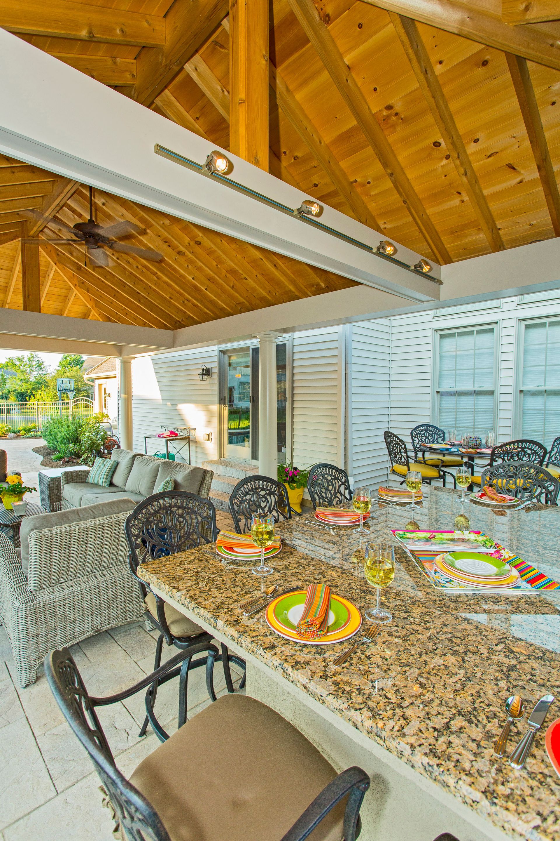 A patio with a table and chairs under a wooden roof.