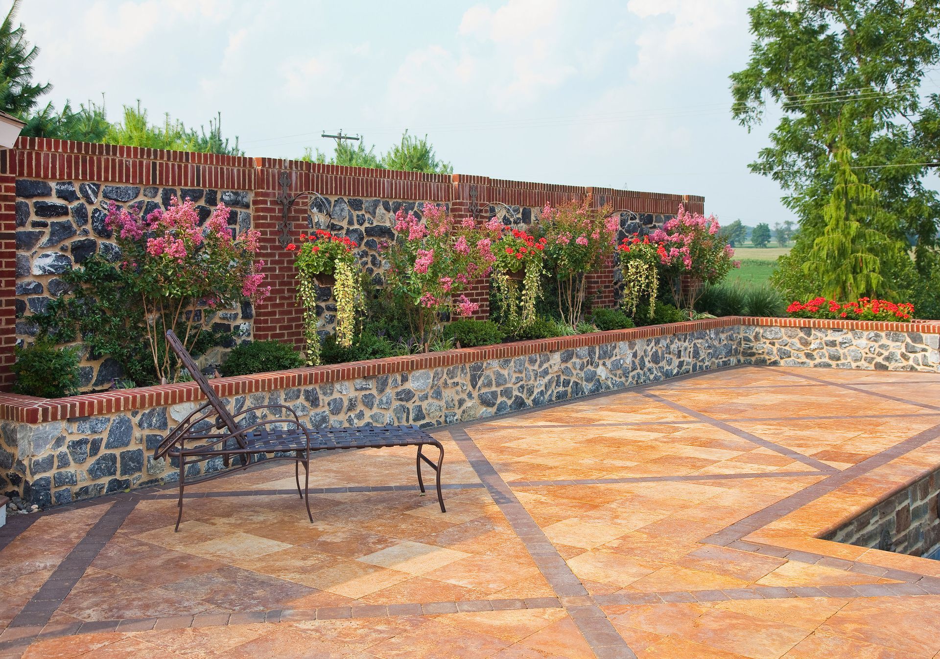 A brick wall surrounds a patio with a bench and chairs.