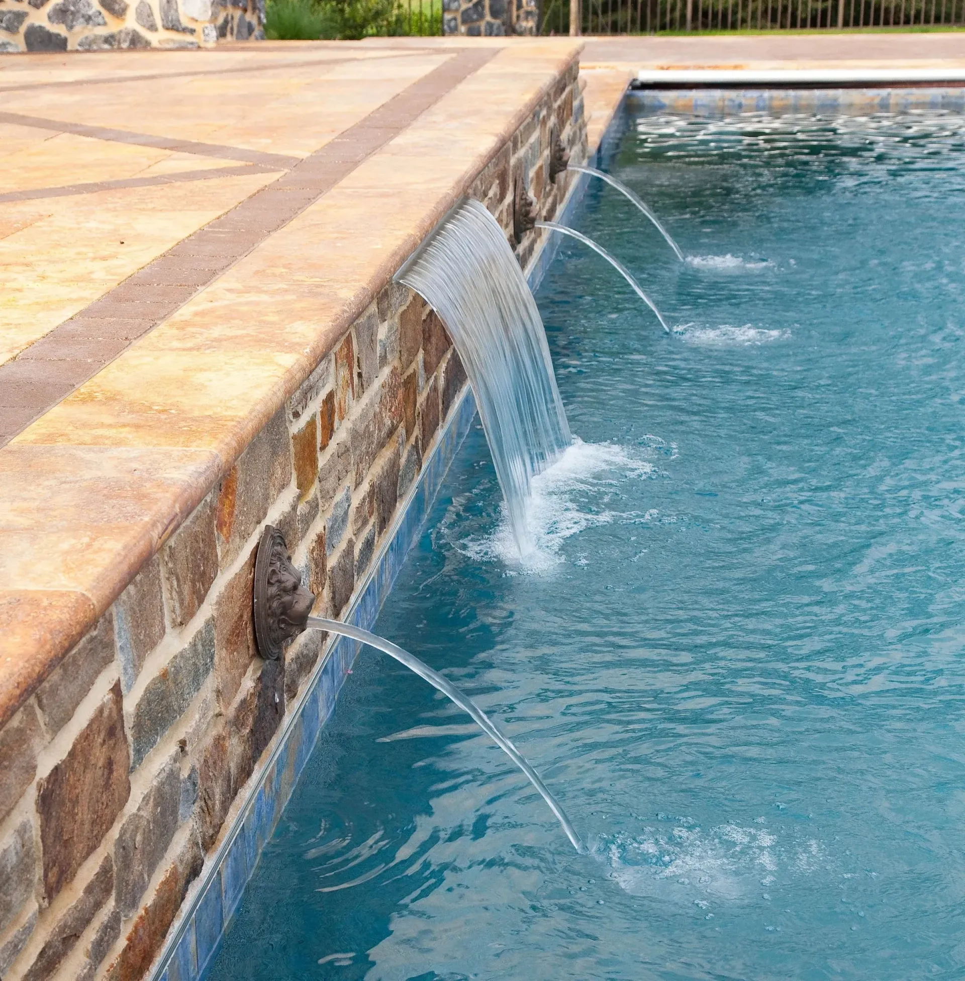 A waterfall is spraying water into a swimming pool