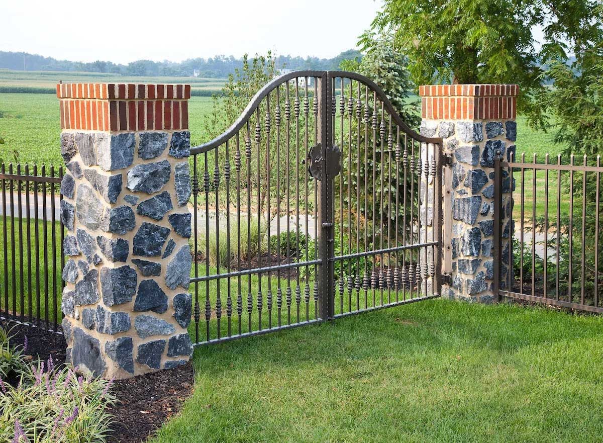 A wrought iron gate is surrounded by stone pillars.