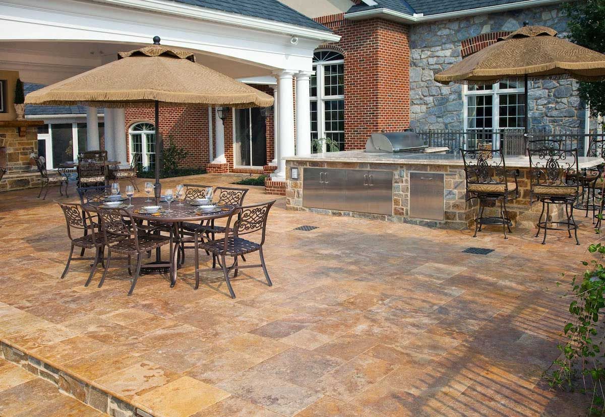 A patio with a table and chairs and umbrellas in front of a house.